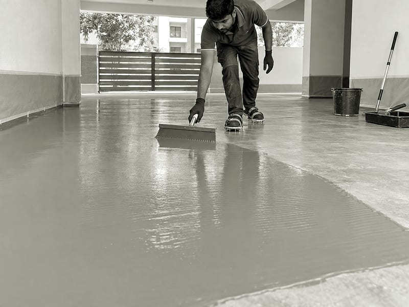A specialist spreading a seamless grey floor coating in a protected garage.